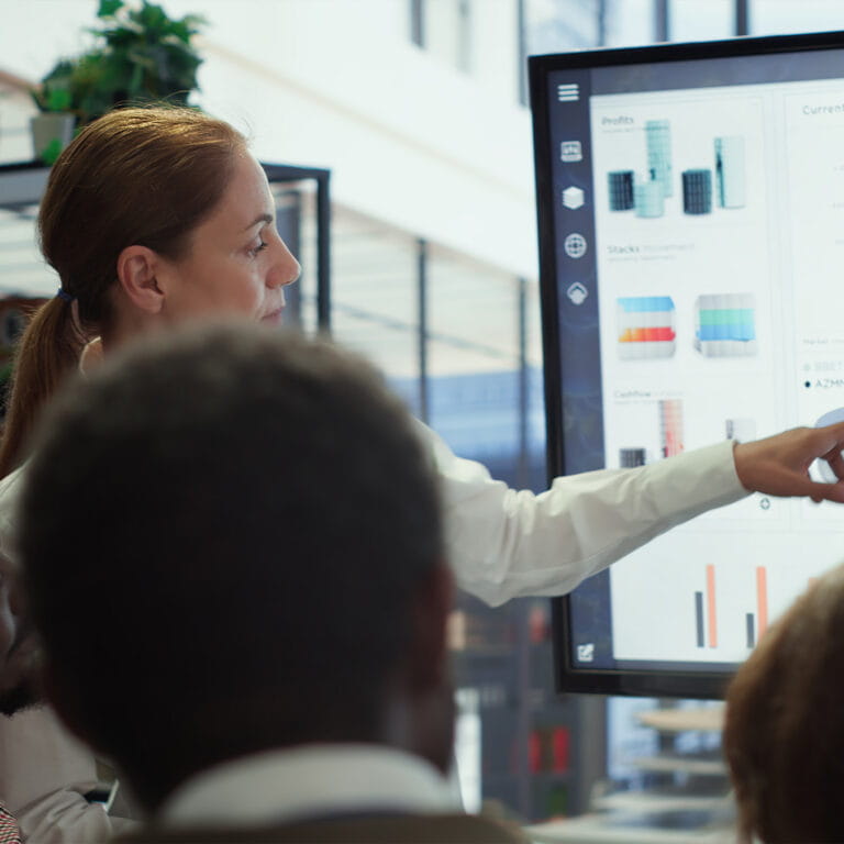 Een senior consultant wijst naar data op het scherm tijdens een teamoverleg