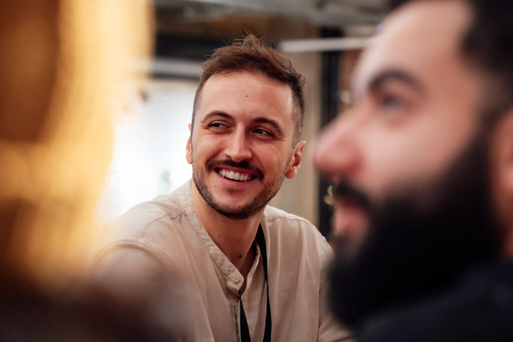 Lachende man in gesprek met collega's tijdens een zakelijke bijeenkomst op kantoor.